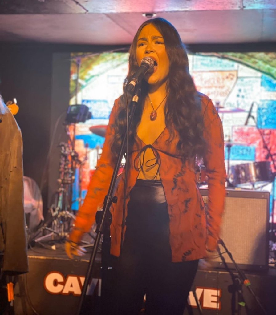 Caitlyn Eve singing into microphone at Cavern